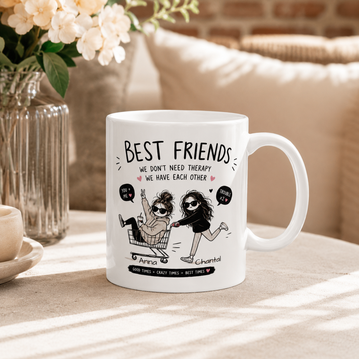 A white ceramic mug with a custom cartoon illustration and the text 'BEST FRIENDS WE DON'T NEED THERAPY WE HAVE EACH OTHER' placed on a table in a warm, sunlit room setting.